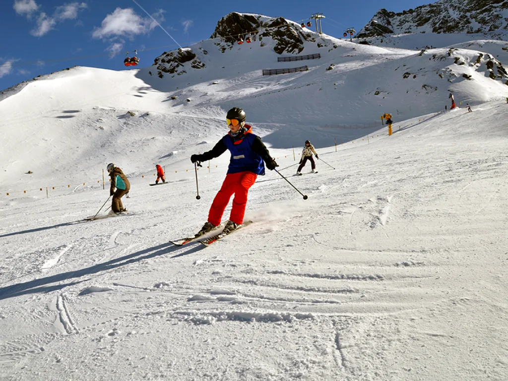 Skifahrer in roter Hose fährt den weiten Hang hinunter.